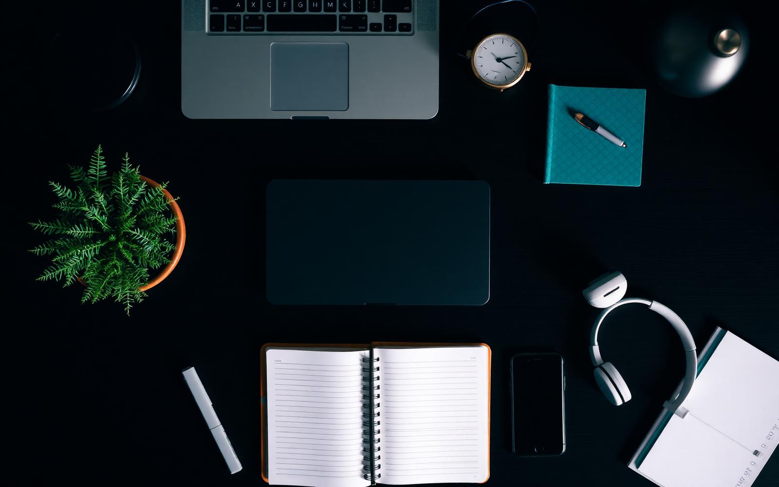 A planner and a laptop on a quiet desk in low light.